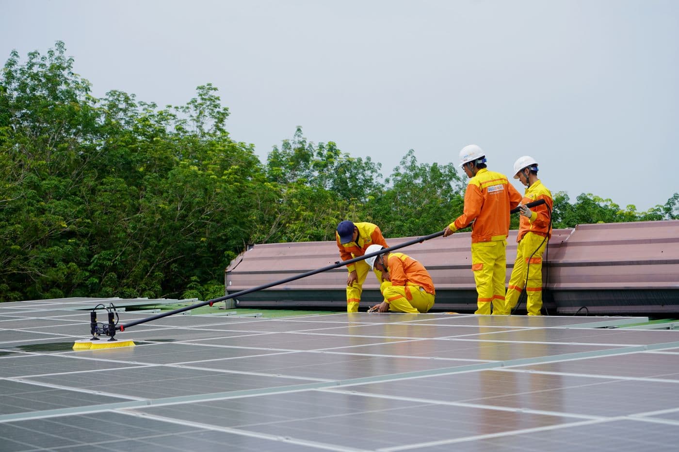 Arbeiter reinigen Photovoltaikmodule auf einem Dach