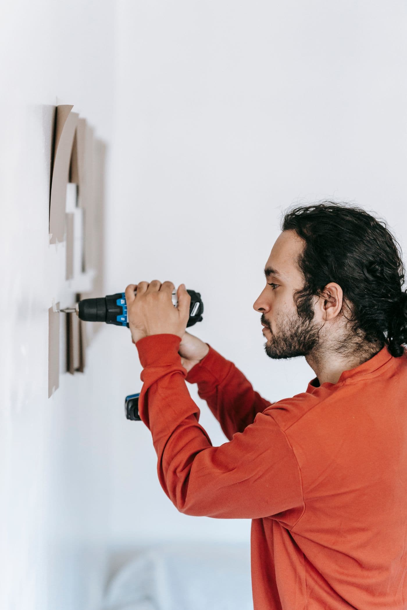 Handwerker montiert mit einem Akkuschrauber etwas an einer Wand